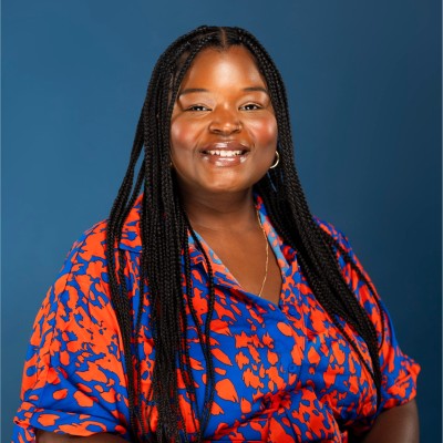 Ronya is a black female with long braided hair and wearing a blue and orange floral blouse.